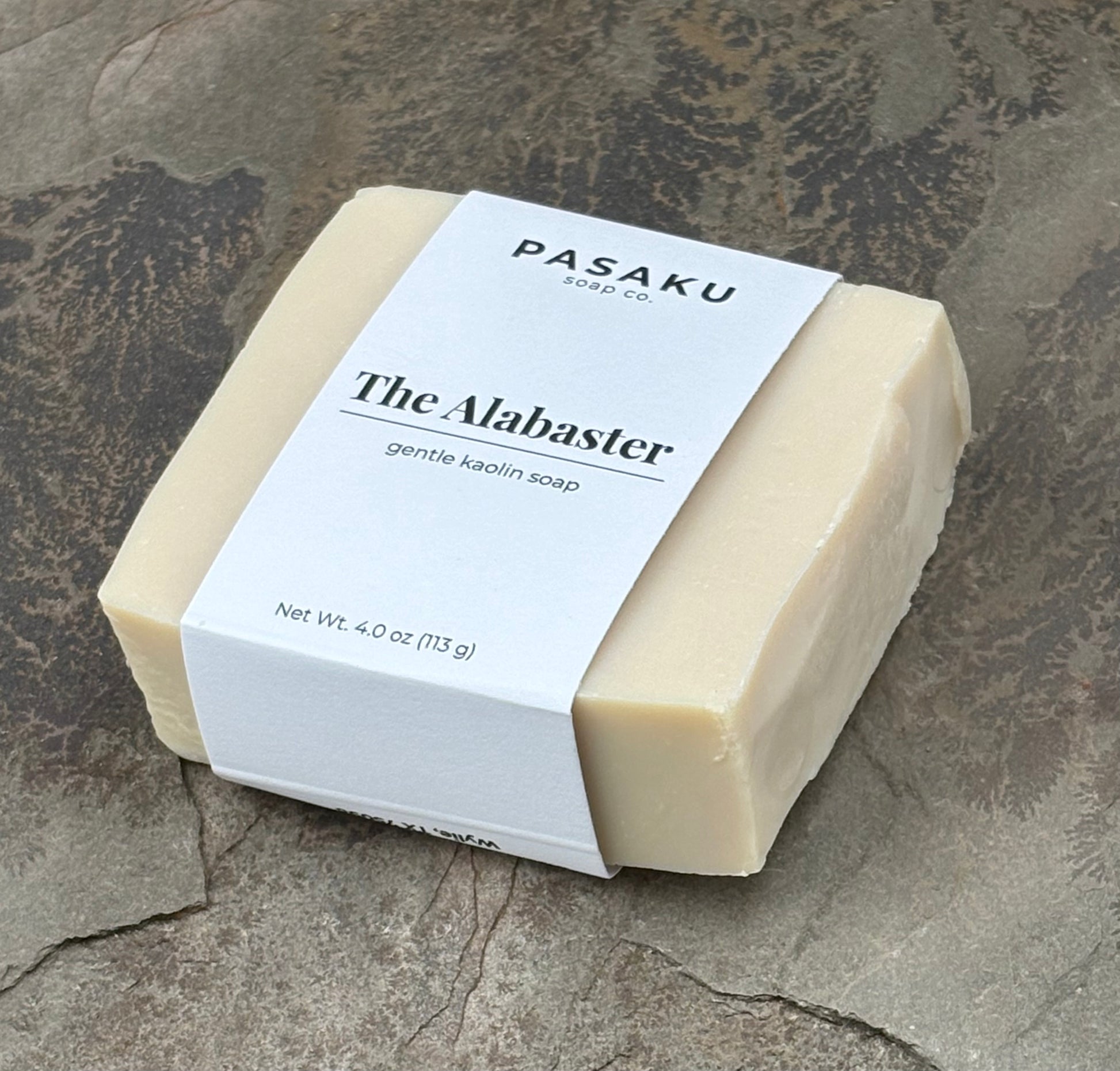 with white wrap around label that has the name of the company, the name of the soap, and the net weight of 4 oz. displayed on a piece of slate